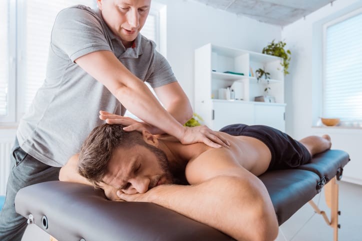 Starting your own massage therapy practice, therapist massages back of man in private practice massage room
