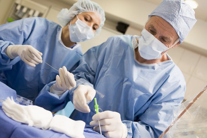 Cardiologist and assistant performing a heart catheterization procedure in an operating room