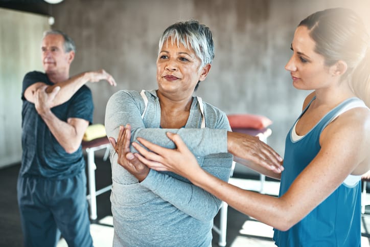 A senior man and woman doing heart failure rehabilitation exercises with the help of a physical therapist