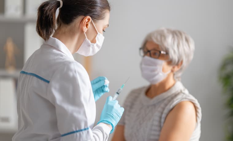 Doctor giving a senior woman a COVID-19 booster shot