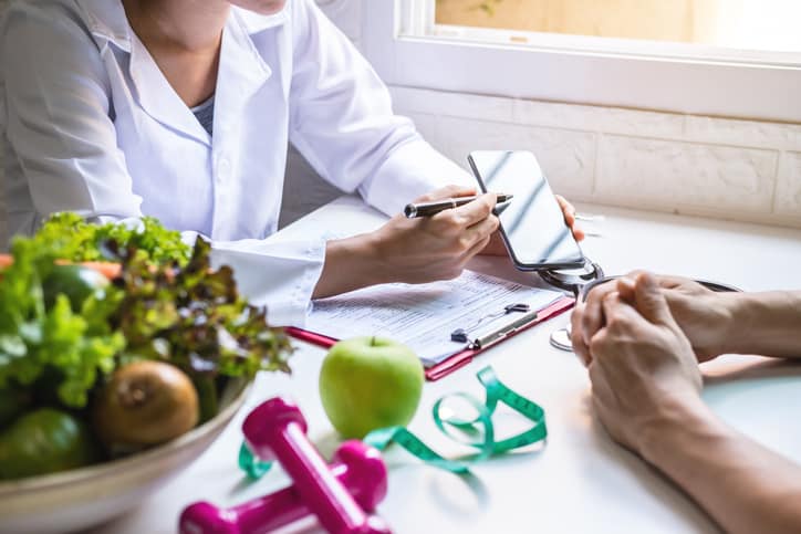 Healthcare professional giving nutrition consultation to patient with healthy fruit and vegetable