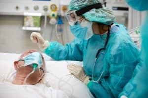 Nurse is comforting an older COVID-19 patient at the ICU