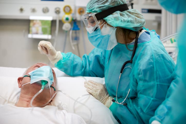 Nurse is comforting an older COVID-19 patient at the ICU
