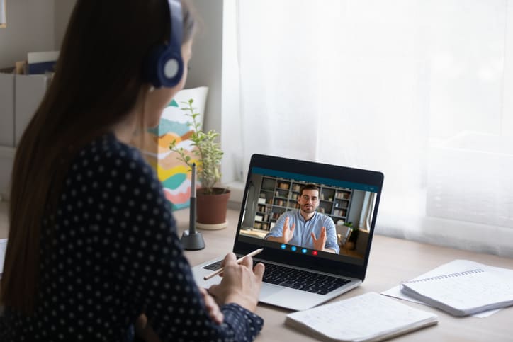 Female student in headphones looking at computer screen, watching on-demand video course