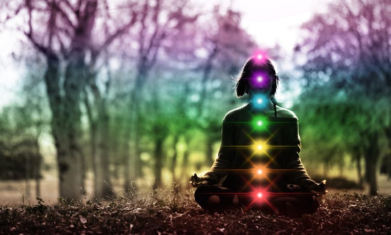Woman meditating in lotus pose, diagram of the seven energy centers, chakra system