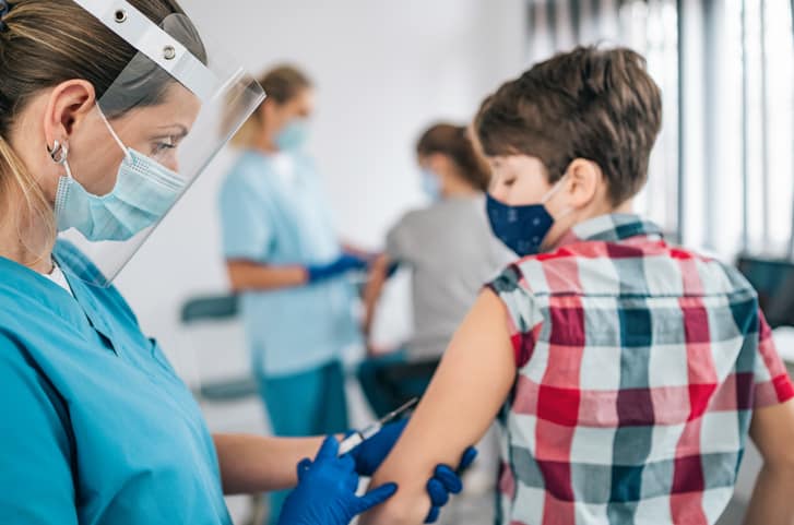Doctor injecting COVID-19 vaccine into young boy's arm