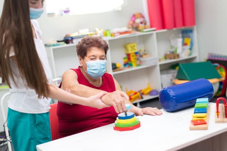Old woman exercising with an occupational therapist after suffering from stroke