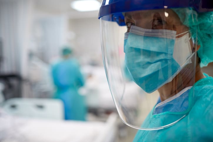 Close up view of a doctor wearing surgical mask and a face shield in hospital COVID-19 unit
