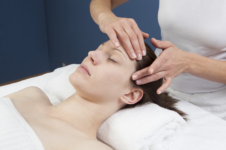 massage therapist massages female patient's head