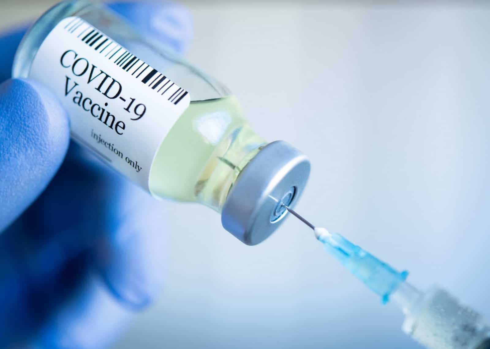 Close-up of COVID-19 vaccine vial and syringe held by gloved hands of healcare worker