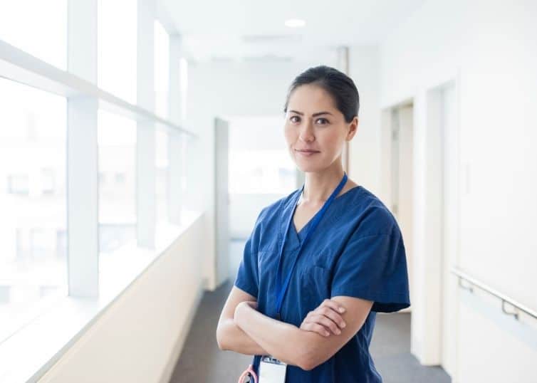 Female nurse leader in scrubs looks confidently into camera