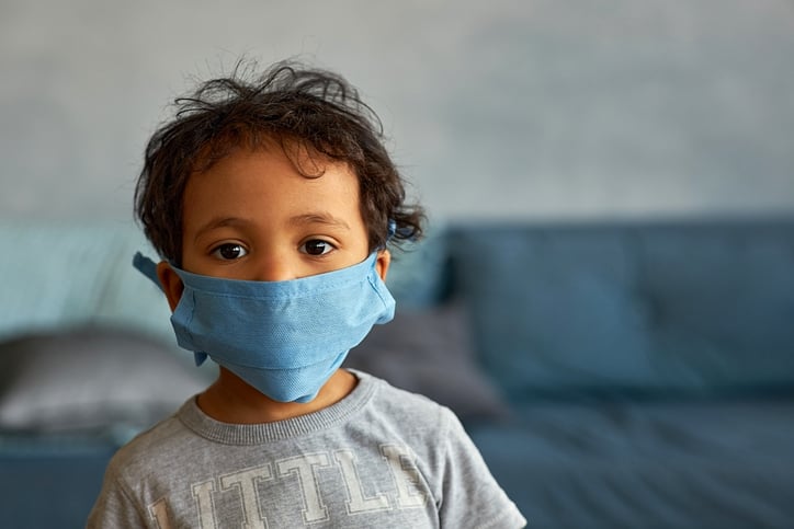 Portrait of a cute toddler boy in mask at home during COVID-19 pandemic