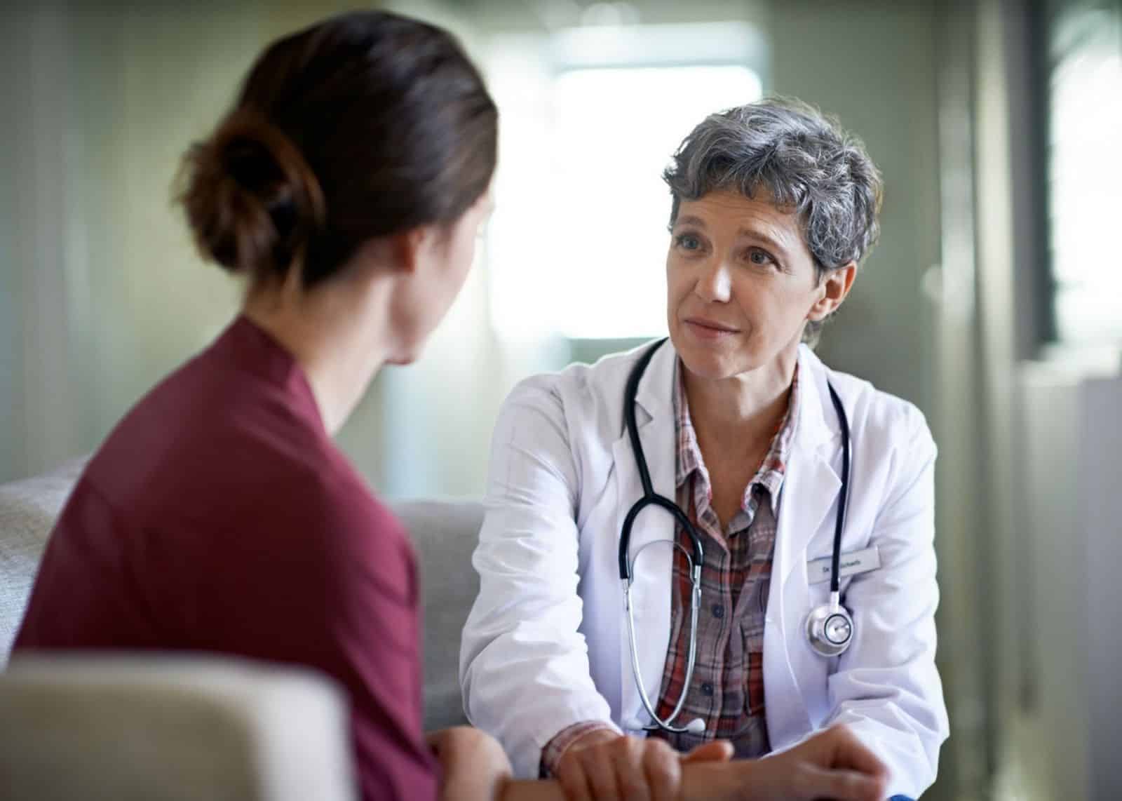 Healthcare provider speaks compassionately with young female patient showing possible signs of domestic violence