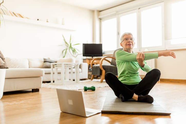 Senior woman exercising at home using an online trainer service