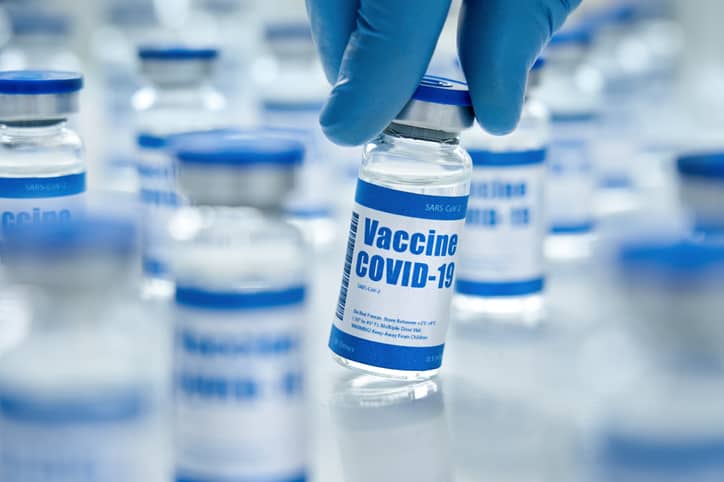 Male doctor hand wears medial glove holding covid 19 corona virus vaccine vial bottle for injection on medical pharmacy background
