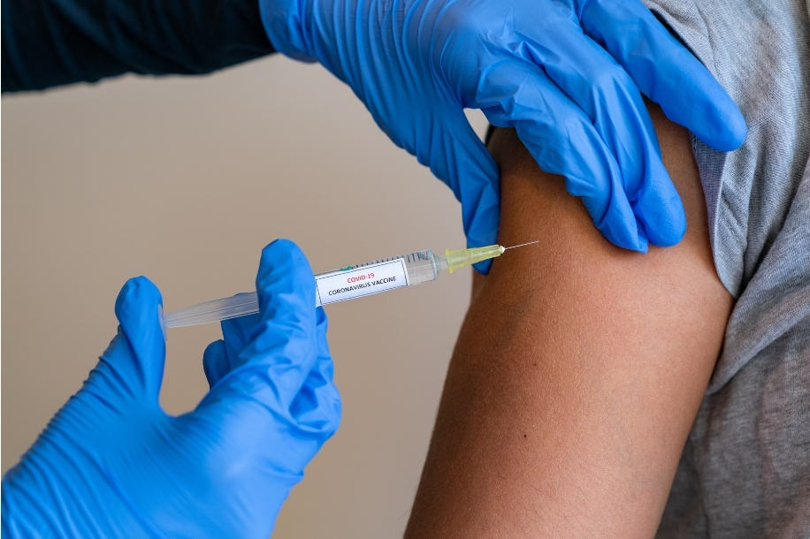 Close-up of gloved hands injecting COVID-19 vaccine into patient's arm