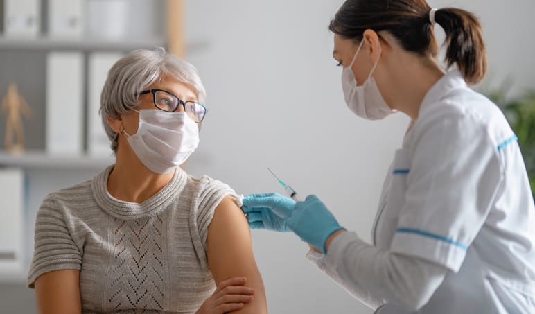 Doctor giving a senior woman a third vaccine dose.