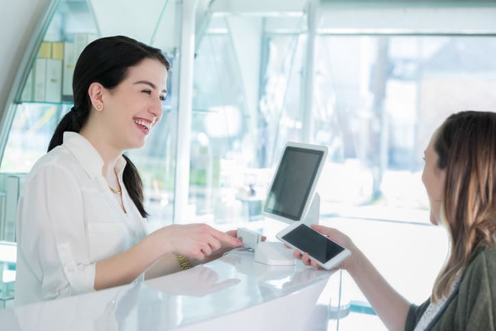 Female hair salon customer uses contactless payment, how to price your cosmetology services concept