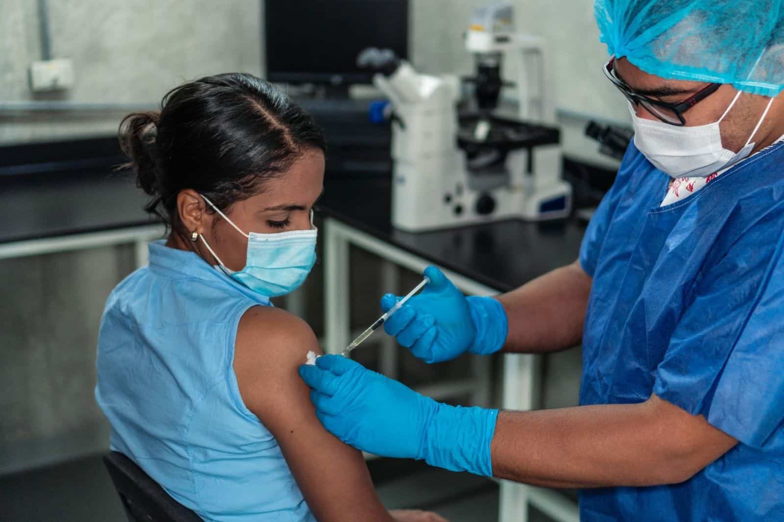 Healthcare worker receiving a COVID-19 vaccination shot from a fellow healthcare worker