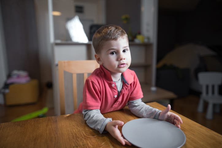 Cute little hungry boy waiting for his dinner. Food insecurity concept.