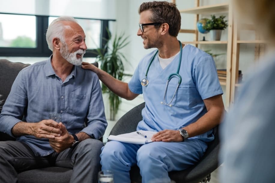 Male nurse comforts chronic pain patient, provides pain relief to mature male patient
