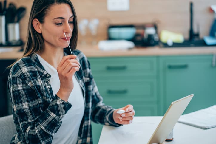 Woman holding self-testing swab, taking rapid COVID-19 home test