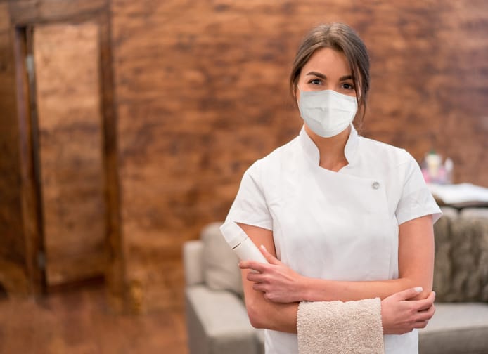 Massage therapist working at a spa and wearing a face mask during the COVID-19 pandemic