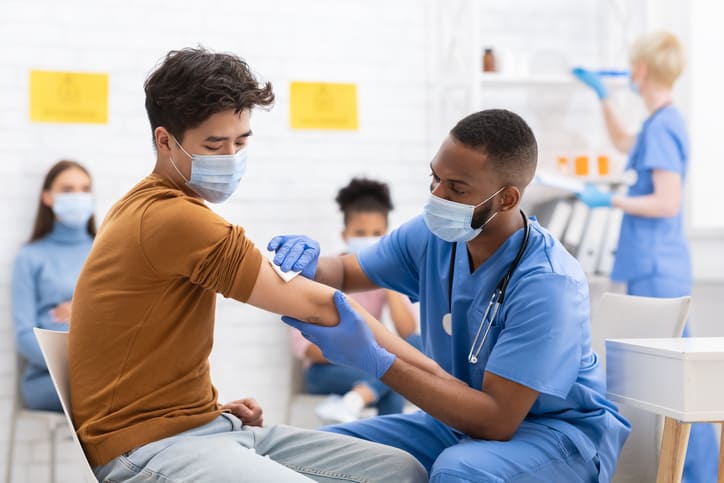 Covid-19 vaccination. Asian male patient getting vaccinated against coronavirus by Covid volunteer nurse.