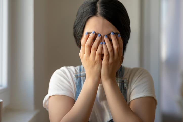 Unhappy young woman, sexual assault victim covers face with hands