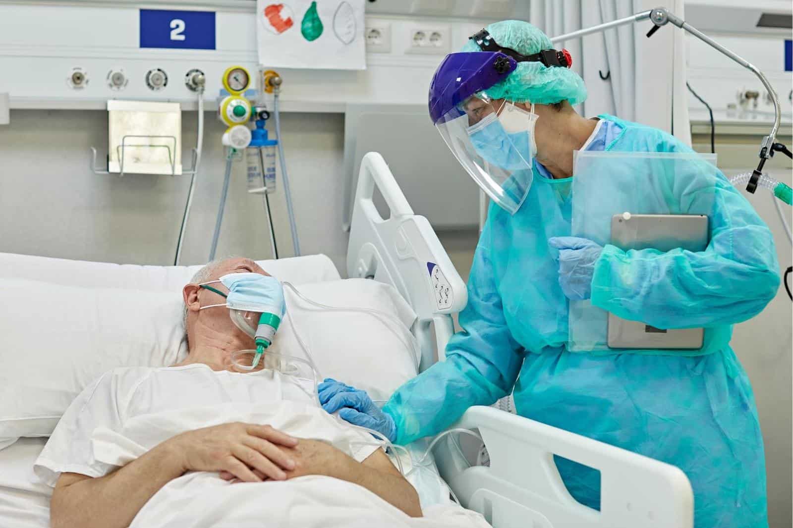 ICU nurse visits bedside of ARDS patient with breathing mask during COVID-19 pandemic