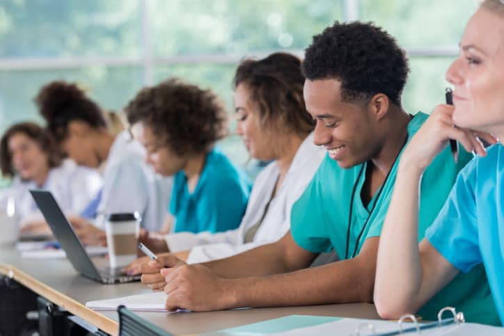 Diverse male and female nursing students take notes during class, training to become forensic nurses
