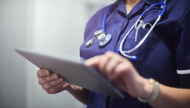 Nurse using digital tablet in hospital or medical office.